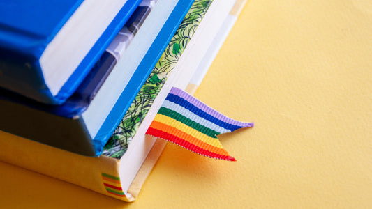 image of classroom textbooks with a pride flag bookmark celebrating gender pronouns in the classroom for lgbtq youth safe spaces